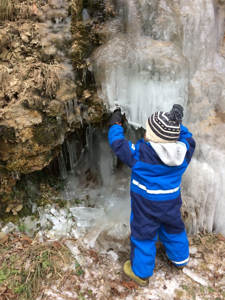 Kind vor gefrorenem Wasserfall